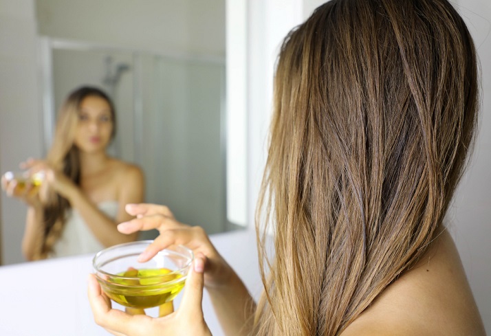 young-woman-applying-olive-oil-mask-hair-front-mirror.jpg